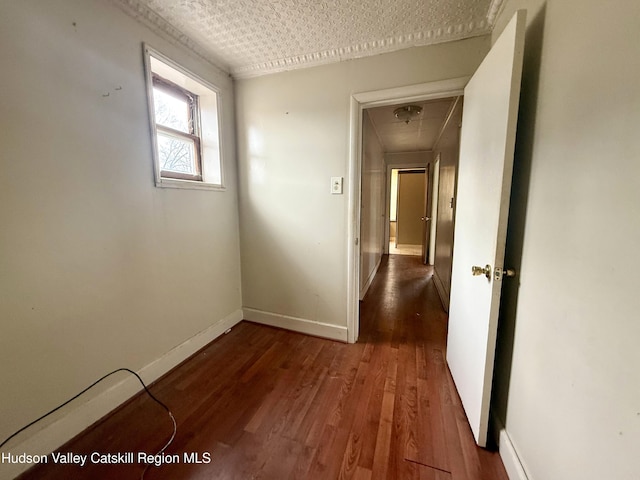 corridor featuring attic access, wood finished floors, and baseboards