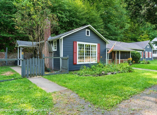 view of front of home with a sunroom, fence, and a front lawn