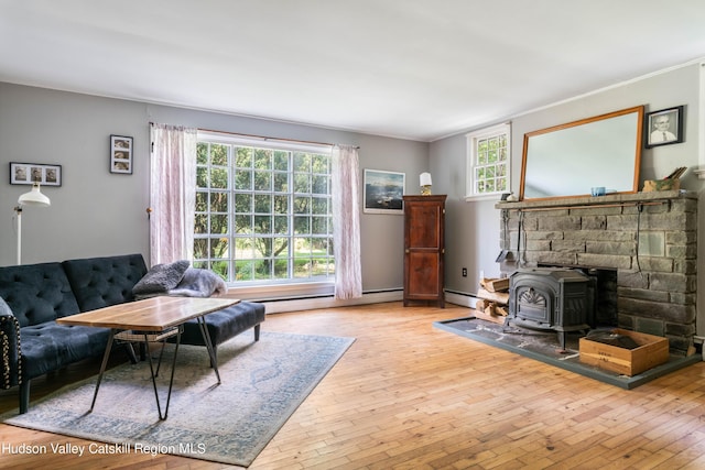 living room featuring a wood stove, a baseboard radiator, ornamental molding, and wood-type flooring