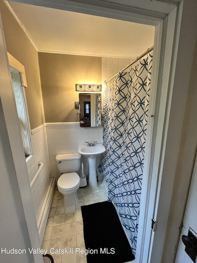 bathroom with a wainscoted wall, tile walls, a baseboard radiator, curtained shower, and toilet