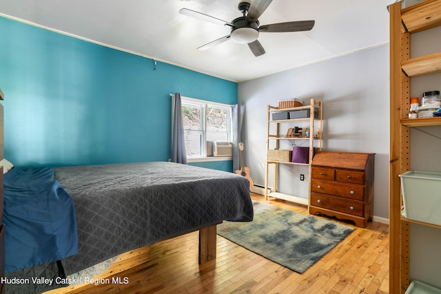 bedroom with hardwood / wood-style flooring, ceiling fan, a baseboard heating unit, and baseboards