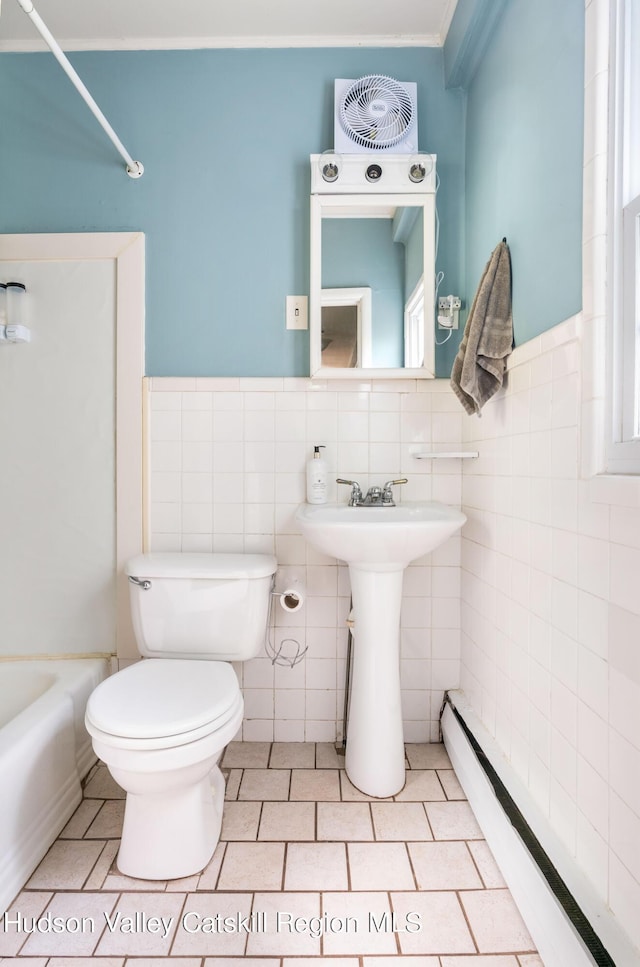 full bath featuring tile walls, toilet, tile patterned floors, a baseboard heating unit, and a sink