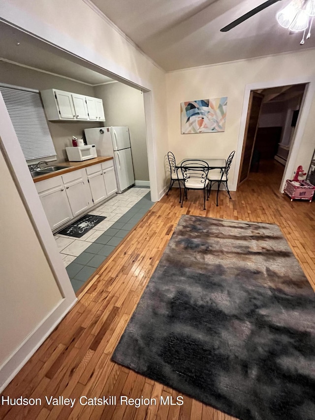 dining space featuring ceiling fan, light wood-style flooring, and baseboards