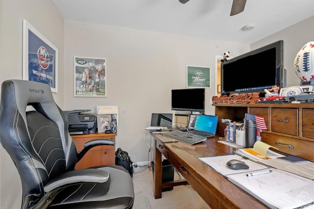 carpeted office space featuring a ceiling fan and baseboards