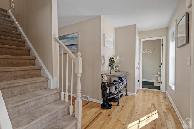 foyer featuring wood finished floors, stairway, and baseboards