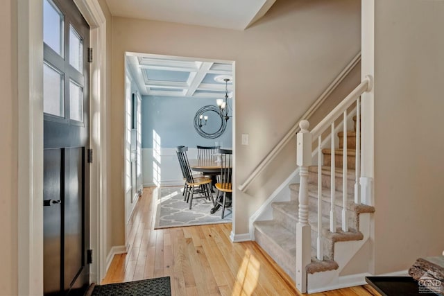stairway with coffered ceiling, wood-type flooring, baseboards, beamed ceiling, and a chandelier