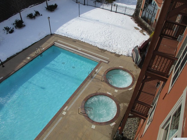 62 Liftside Dr Unit 306F1, Hunter, NY 12442 - snow covered pool with a community pool, a hot tub, a patio, and fence