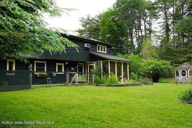 rear view of property featuring a yard and a wall unit AC