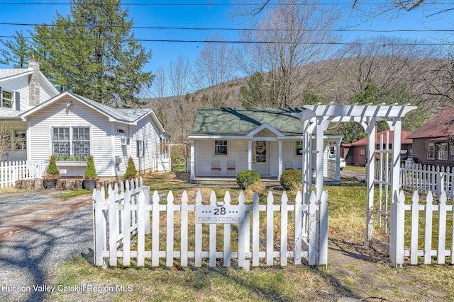 bungalow-style home with a porch, a mountain view, and a fenced front yard