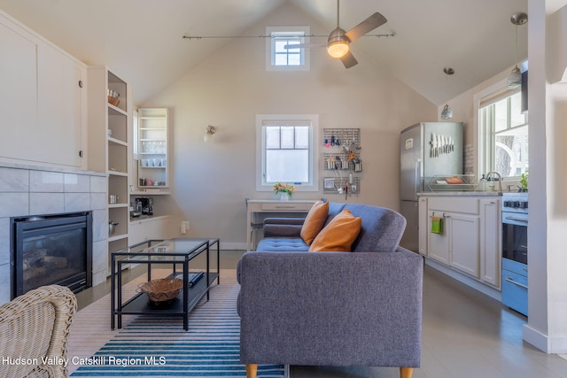 living room with a ceiling fan, baseboards, high vaulted ceiling, and a fireplace