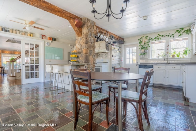 dining room with stone tile floors, french doors, and ceiling fan with notable chandelier