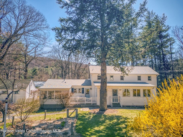 back of property with a lawn and roof with shingles