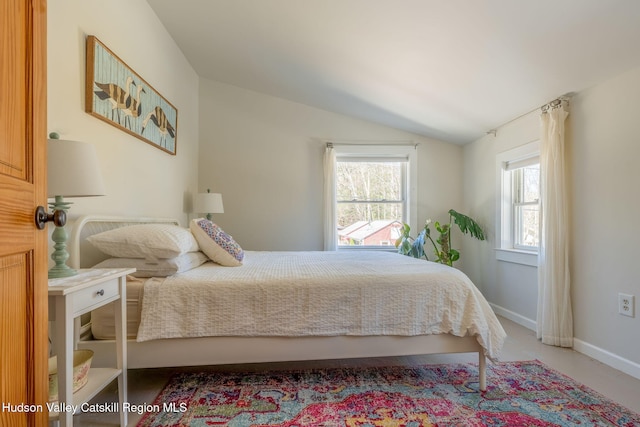 bedroom with lofted ceiling and baseboards