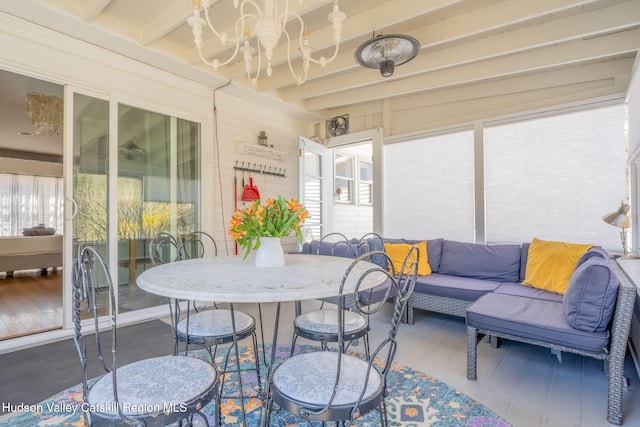 sunroom featuring a chandelier, wood finished floors, beam ceiling, and an outdoor hangout area