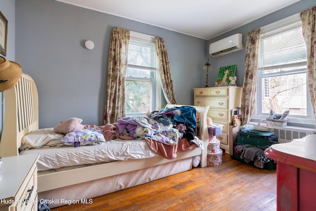 bedroom with wood finished floors and a wall mounted air conditioner