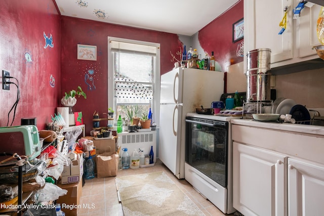 kitchen featuring light tile patterned floors, white cabinets, light countertops, and freestanding refrigerator