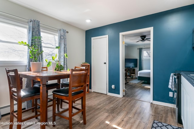 dining room with a ceiling fan, wood finished floors, and baseboards