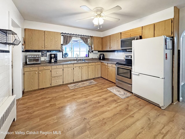 kitchen with ceiling fan, decorative backsplash, light wood-type flooring, radiator heating unit, and stainless steel appliances