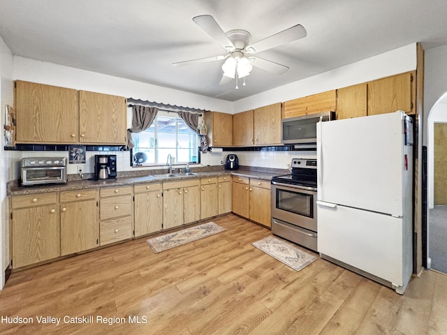 kitchen with sink, light hardwood / wood-style flooring, decorative backsplash, ceiling fan, and appliances with stainless steel finishes