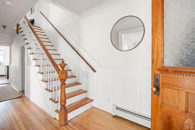 7 Mckinstry Pl, Hudson, NY 12534 - staircase with a baseboard radiator, hardwood / wood-style floors, crown molding, a wainscoted wall, and a decorative wall