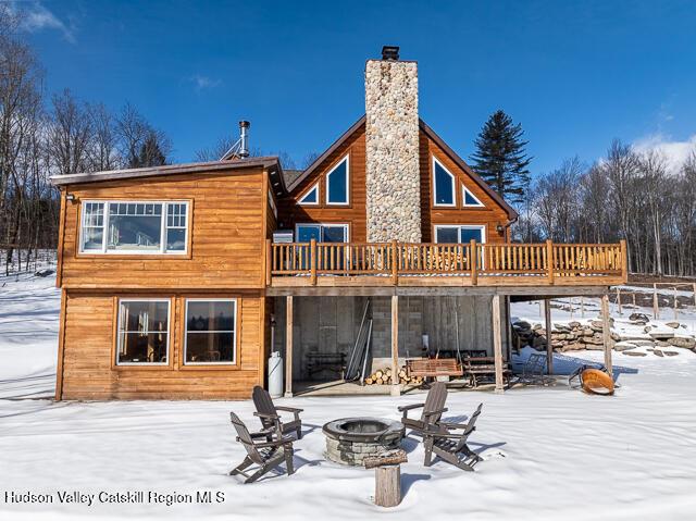 snow covered house with a wooden deck and a fire pit