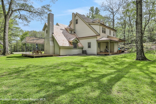 back of property featuring a lawn, a pergola, and a deck