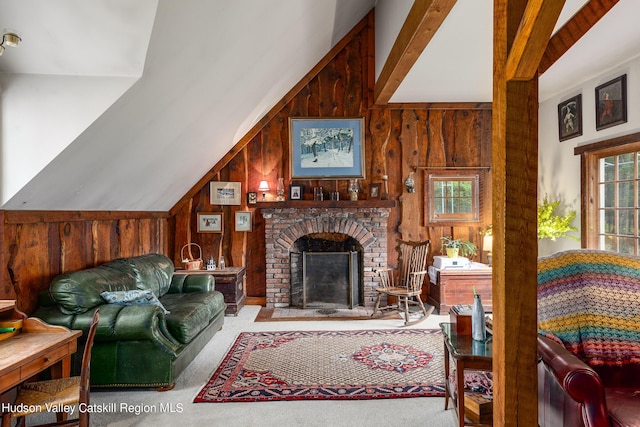 carpeted living room with lofted ceiling with beams, wood walls, and a fireplace