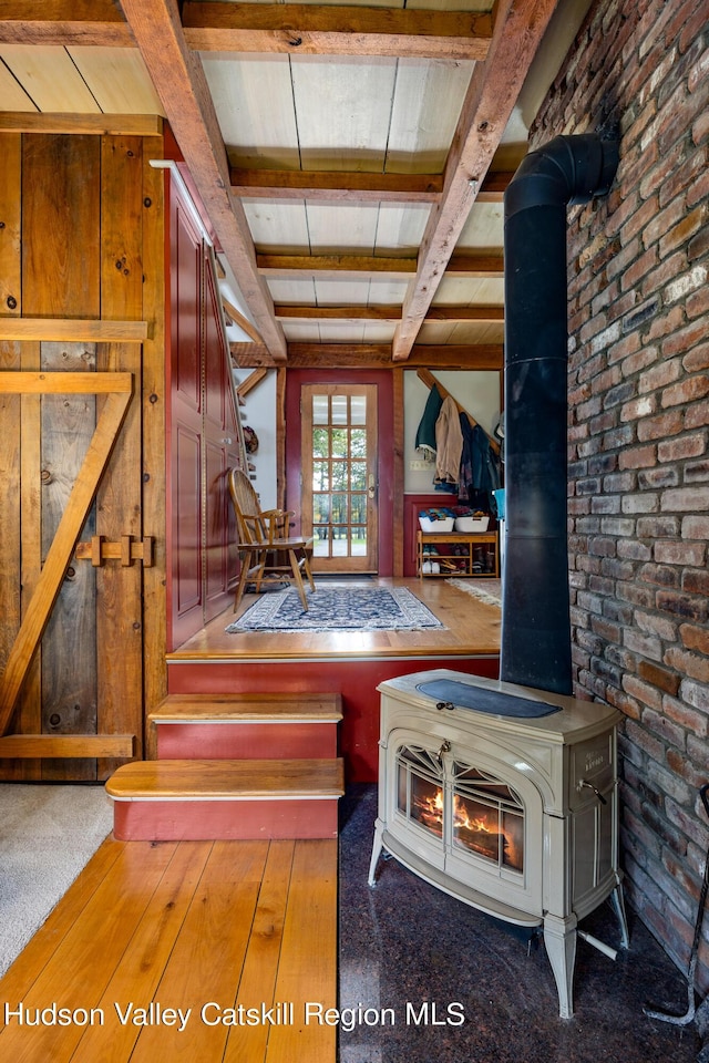 interior space with hardwood / wood-style flooring, beamed ceiling, and brick wall