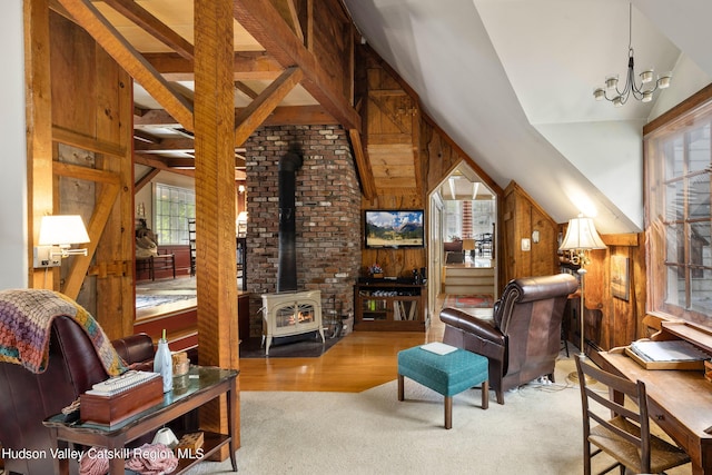 living room with a wood stove, light hardwood / wood-style flooring, high vaulted ceiling, a chandelier, and wooden walls