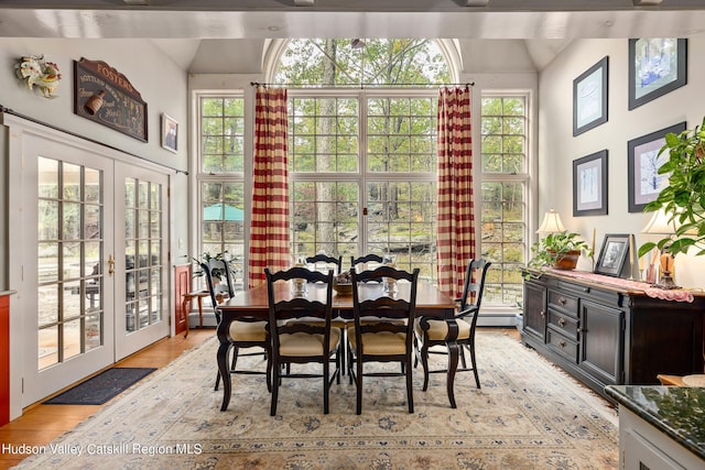 dining space with french doors, light wood-type flooring, and a baseboard heating unit