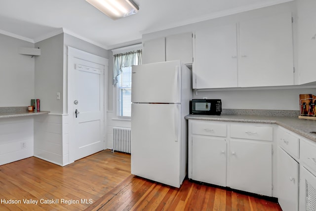 kitchen with white refrigerator, light wood-type flooring, white cabinetry, and radiator