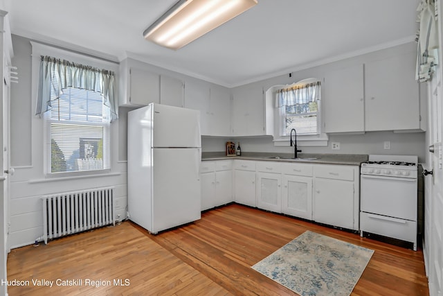 kitchen with white cabinets, white appliances, sink, and radiator