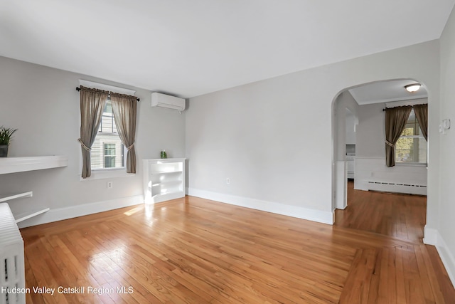 empty room featuring wood-type flooring, baseboard heating, and a wall unit AC