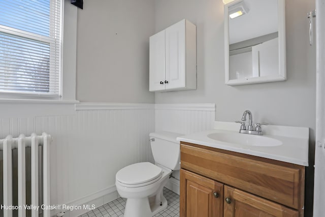 bathroom with tile patterned flooring, vanity, toilet, and radiator