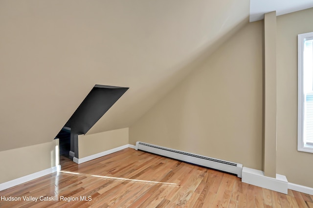 additional living space with hardwood / wood-style floors, lofted ceiling, and a baseboard radiator