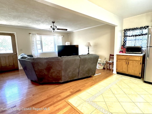 living room featuring a textured ceiling, ceiling fan, light hardwood / wood-style floors, and crown molding