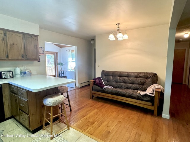 kitchen featuring kitchen peninsula, a kitchen breakfast bar, light wood-type flooring, a baseboard heating unit, and an inviting chandelier