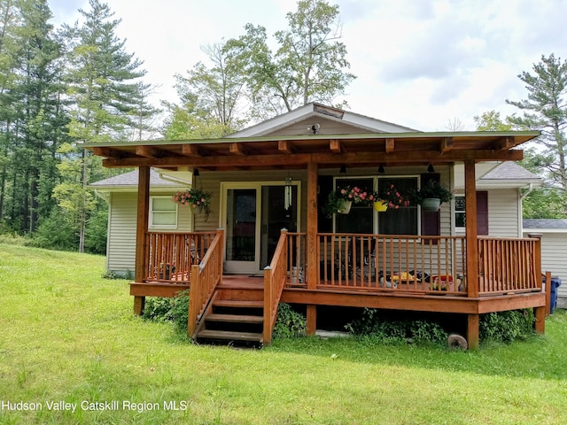 rear view of property featuring a lawn and a wooden deck