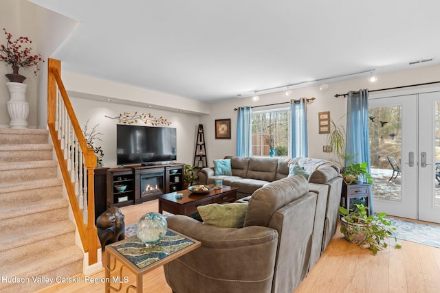 living room with rail lighting, french doors, and light wood-type flooring