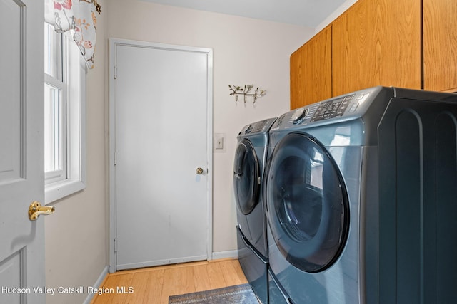 washroom with cabinets, light hardwood / wood-style floors, and washing machine and dryer