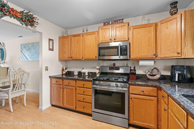 kitchen with dark stone countertops, light hardwood / wood-style flooring, and stainless steel appliances