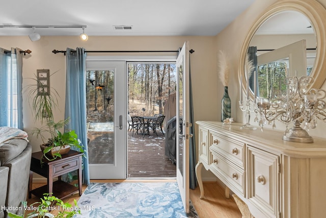 doorway to outside with french doors, rail lighting, and light hardwood / wood-style floors