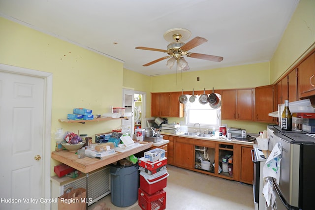 kitchen featuring brown cabinetry, ceiling fan, a sink, and light countertops