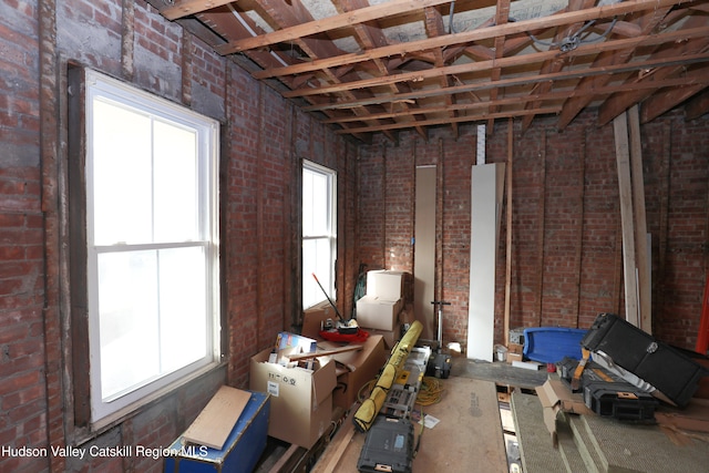miscellaneous room featuring brick wall and a healthy amount of sunlight