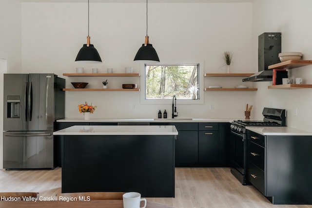 kitchen featuring sink, black gas range oven, light hardwood / wood-style flooring, stainless steel refrigerator with ice dispenser, and pendant lighting