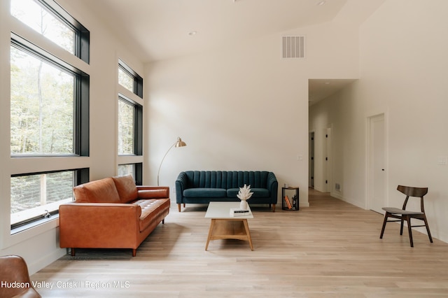 living room featuring high vaulted ceiling, a healthy amount of sunlight, and light wood-type flooring