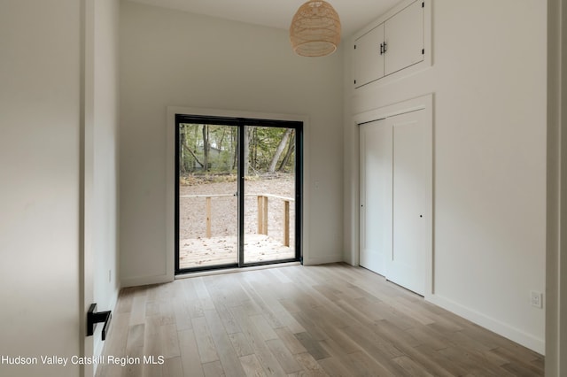 unfurnished bedroom with a high ceiling, light wood-type flooring, and a closet