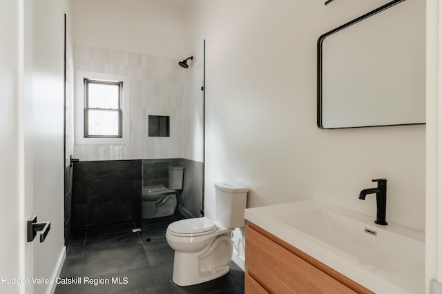 bathroom featuring tile patterned flooring, vanity, toilet, and tiled shower