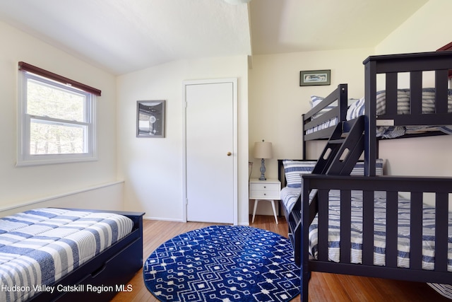 bedroom with vaulted ceiling and wood finished floors