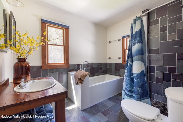 full bath with a sink, toilet, tile walls, a bath, and curtained shower